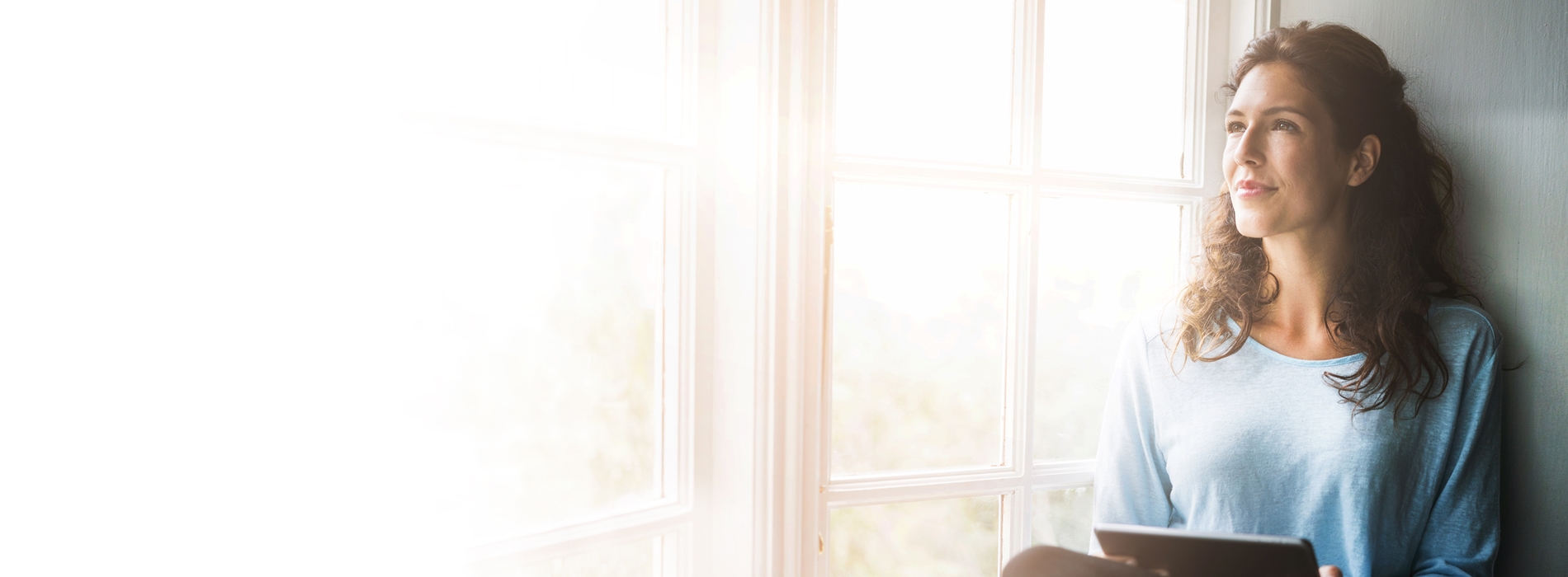 Women using tablet looking out home window
