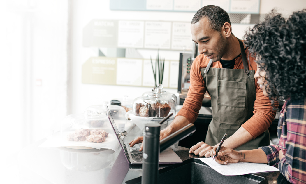 Two people at a desk using a laptop